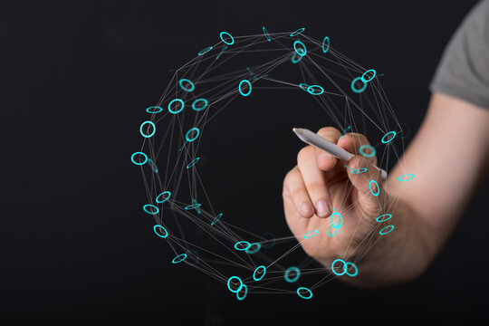 Hand with a digital pen interacts with a holographic sphere representing technology, data, or a network. Conceptual image of innovati