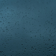 A rainy day window view. Rain drops on window. Condensed rain drop on the car glass window on a rainy day. Dew moisture condensation on wet mirror background. Fresh weather. Water raindrop bg