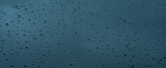 A rainy day window view. Rain drops on window. Condensed rain drop on the car glass window on a rainy day. Dew moisture condensation on wet mirror background. Fresh weather. Water raindrop bg