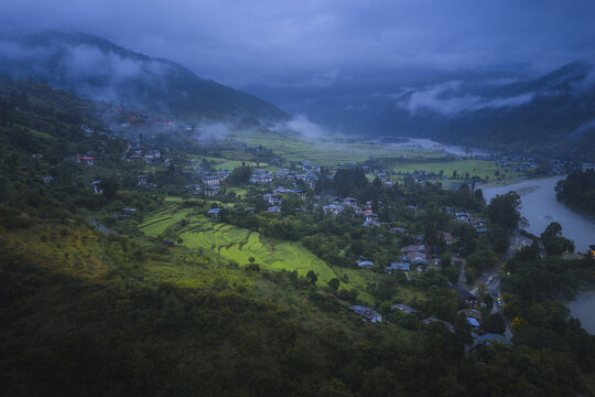 Aerial view of the confluence of rivers at Punakha Dzong, nestled among verdant hills under a misty sky, Punakha, Punakha, Bhutan.