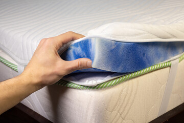 Hand is touching mattress inner filling. Topper mattress with a core of pressure-relieving blue gel foam. Adapts to body and leads away excess heat.