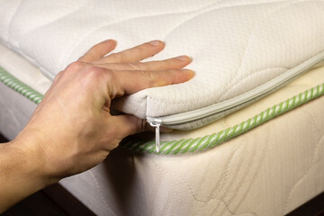 Hand is touching mattress filled with coconut chips. Firm orthopedic mattress topper.