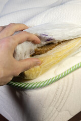 Hand is touching mattress inner filled with coconut chips. Firm orthopedic mattress topper. Vertical photo.