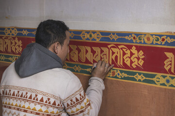 Gangtey Monastery, Bhutan - 20 September 2025: View of an artisan meticulously painting vibrant Tibetan script onto the monastery's walls, blending tradition with artistry.