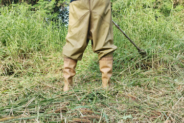 A man stands cutting grass on a clear day.