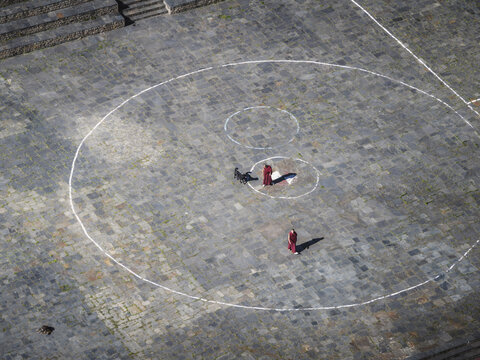 Haa, Bhutan - 26 September 2025: Aerial view of monks in red robes walking across the stone courtyard of Haa Dzong, defined by bright white circles.