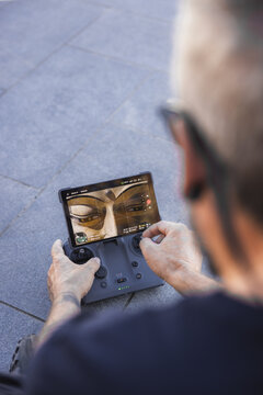 View of a person holding a drone controller with a screen displaying an image of Buddha's face, capturing the cultural essence, Thimphu, Bhutan.