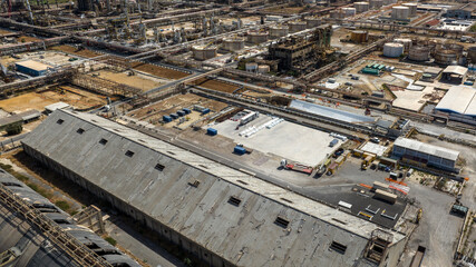 Aerial view of a large industrial area. It is an oil refinery and a large petrochemical complex. There are large storage tanks and complex piping systems.