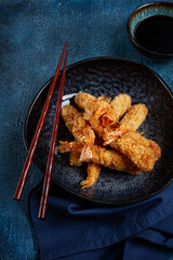 shrimp in tempura, deep fried, on a black plate, with soy sauce, close-up, top view, no people,