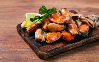 mussels without shell, boiled, mussels, peeled, on a chopping board, with lemon and parsley, mussels in Chilean, top view, no people,