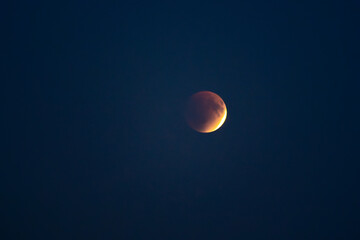 Blood red moon in night sky. Celestial prophecy. Lunar eclipse in dramatic red color with a cosmic sparkle. A symbol of transformation.