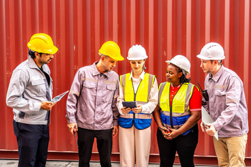 Happy diverse group of engineers workers checking inventory with tablet device in the container yard background. This is a freight transportation and distribution warehouse.