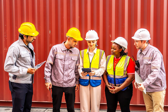 Happy diverse group of engineers workers checking inventory with tablet device in the container yard background. This is a freight transportation and distribution warehouse.