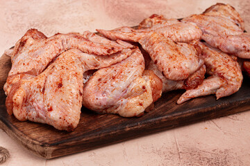Chicken wings, marinated and laid out on a wooden platter, ready for cooking, grilling or baking, in a home kitchen, there are no people