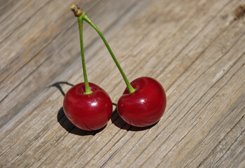 two juicy ripe cherries on a wooden old table