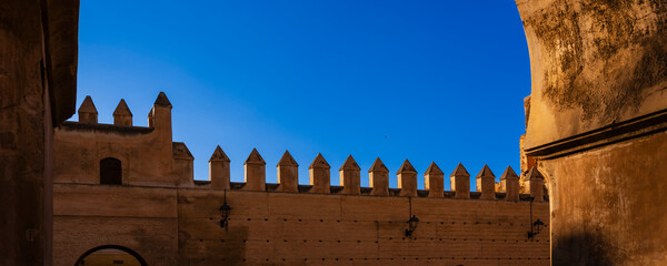 Ancient fortress walls with pointed towers under a clear blue sky. Fez, Fez-Meknes, Northern Inland Morocco