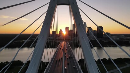 Margaret Hunthill Drives modern bridge architecture at sunset, featuring sturdy structure and bustling thoroughfare with cars driving across its length, capturing urban energy and daily routine.