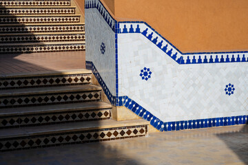 Outdoor stairs and wall with intricate blue and white mosaic tiles in sunlight. Marrakesh, Morocco
