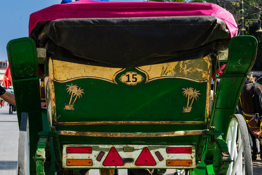 Vibrant horse-drawn carriage with green and gold accents, adorned with palm tree motifs. Marrakesh, Morocco