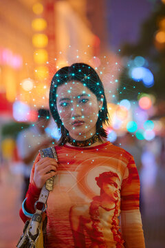 Woman on street with digital facial recognition grid and blurred colorful lights. Shanghai, China