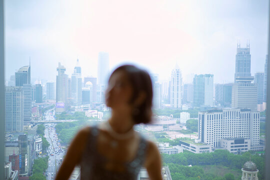Blurry foreground silhouette with a city skyline background under a cloudy sky. Shanghai, China 