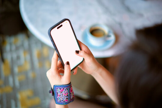 A person seated at a table using a smartphone with a cappuccino on the side. Shanghai, China
