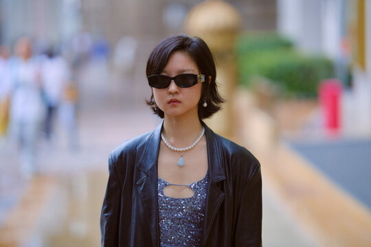 Woman in stylish outfit and sunglasses walks confidently on an urban street. Shanghai, China