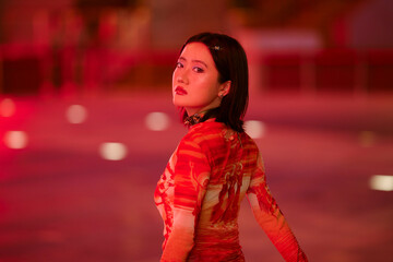 Woman in red dress looks over shoulder in vibrant, dimly lit space with red ambiance. Shanghai, China