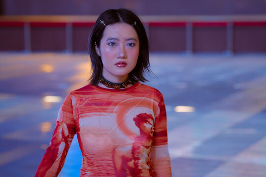 Young woman with short black hair in a vibrant red dress walking indoors. Shanghai, China