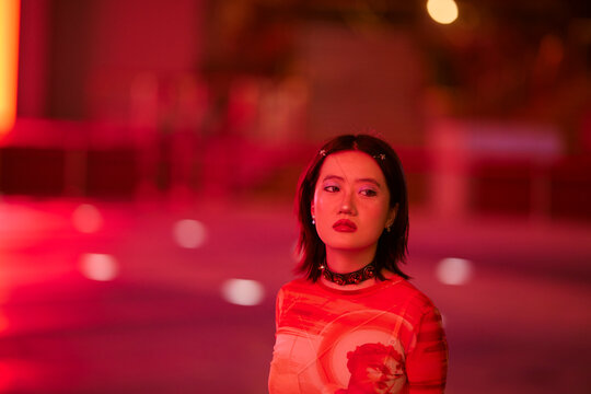 Woman in a red-lit atmosphere, wearing a choker and red lipstick, gazing to her left. Shanghai, China