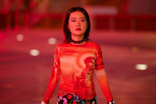 Woman in red dress looks over shoulder in vibrant, dimly lit space with red ambiance. Shanghai, China