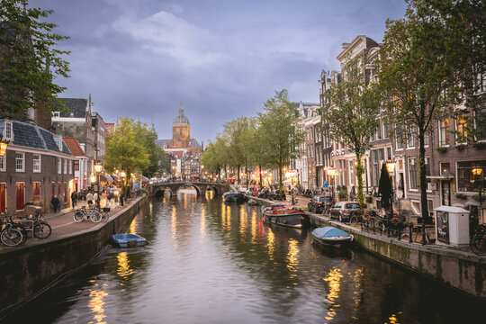 Charming canal scene at dusk with historic buildings and streetlights reflecting in the water. Amsterdam,. Netherlands