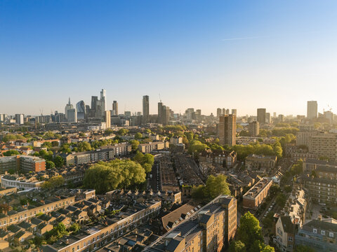 Aerial view of a cityscape with skyscrapers and residential areas under a clear blue sky. London, UK