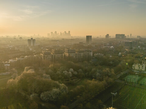 Aerial view of a city at sunrise with hazy skyline and surrounding parkland. London, UK
