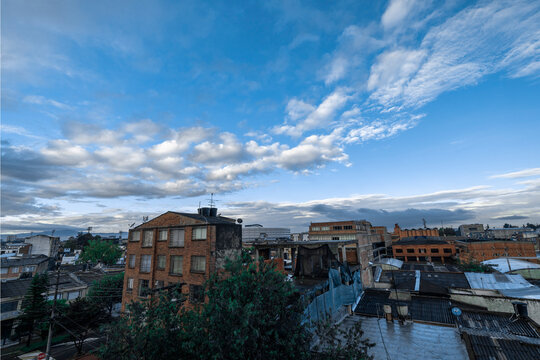 Urban skyline under a vast, cloudy blue sky with various buildings and rooftops. Bogota, Colombia