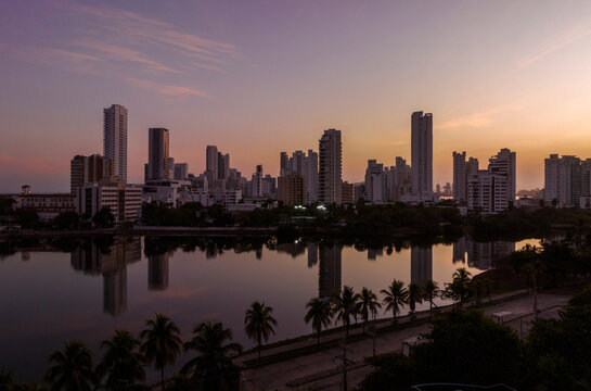 City skyline at dusk with tall buildings and palm trees reflecting in calm water. Cartagena, Colombia