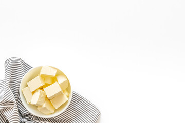 Butter sliced in white bowl with napkin, top view