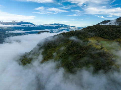 Lush green mountains partially covered with clouds under a bright blue sky. Choachi, Colombia