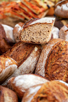 Assortment of rustic crusty bread loaves with seeds and herbs on display. Lyon, France