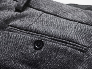 Close-up of a textured gray fabric with a black button and detailed stitching.