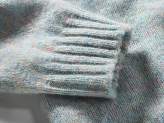 Close-up of a light blue knitted sweater sleeve in soft wool texture.