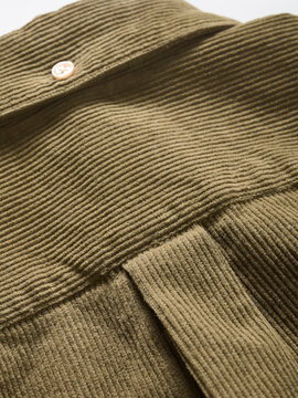 Olive green ribbed fabric texture with button detail on textured surface