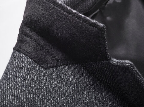 Close-up of a tailored black coat collar with fine stitching detail.