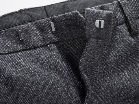Close-up of a black and white herringbone pattern trouser waistband with metal hooks.