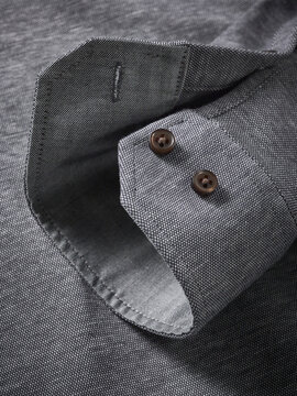 Close-up of a textured gray fabric shirt sleeve with dark buttons for a sleek look