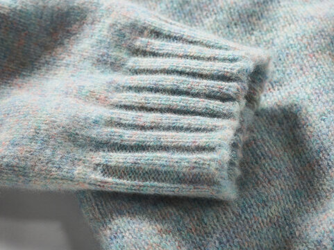 Close-up of a light blue knitted sweater sleeve in soft wool texture.