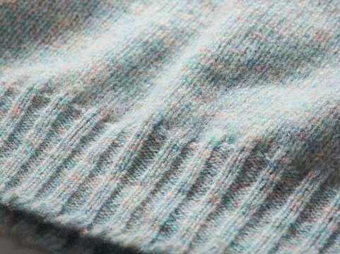 Close-up of a soft, textured fabric with subtle pastel colors and ribbed knitting pattern.