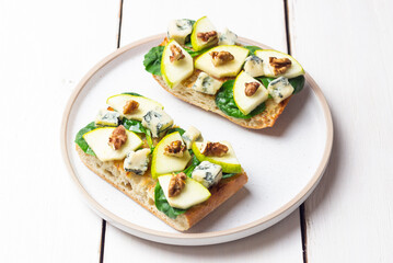Bruschetta with spinach, honey, blue cheese, pear, and nuts. Healthy eating. Vegetarian food.