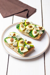 Bruschetta with spinach, honey, blue cheese, pear, and nuts. Healthy eating. Vegetarian food.
