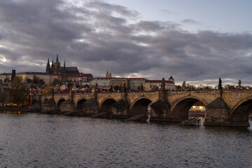 Castle of Prague and Charles bridge reflected on Vltava river at sunset